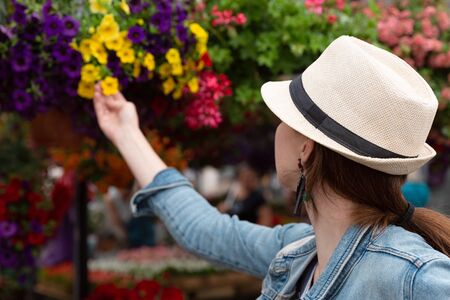 Young woman shopping in an outdoors fresh urban flowers market, buying and picking from a large variety of colorful floral bouquets during a sunny day in the cityの写真素材