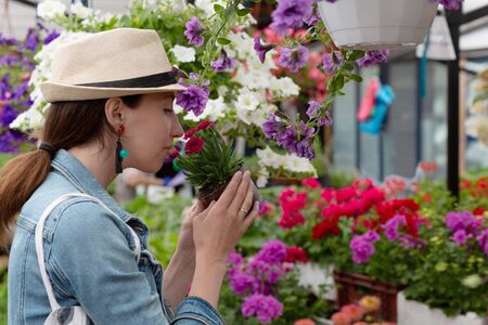 Young woman shopping in an outdoors fresh urban flowers market, buying and picking from a large variety of colorful floral bouquets during a sunny day in the cityの写真素材