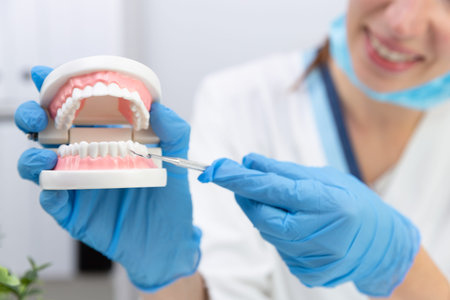 Female dentist holding professional stomatology tool and pointing at the teeth model. Dental hygiene...