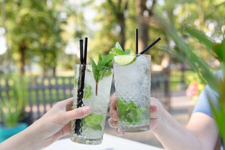 Two women drinking mojito cocktail at outdoor bar restaurant. Summer celebration fun festivalの写真素材