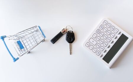 Car purchase concept. Empty shopping cart , car keys and calculator on white tableの写真素材