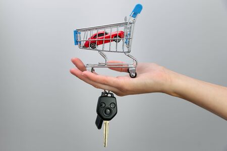 Car purchase concept. Red toy car and car keys in metal shopping cartの写真素材