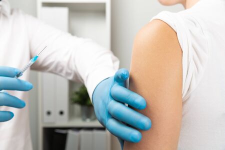 Doctor giving patient vaccine, flu shot. Doctor making a vaccination in the shoulder of patientの写真素材