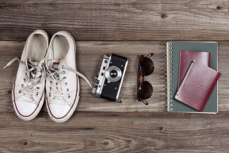 Essentials for modern young person travel. Sneakers, camera, sunglasses, notebook, passport and hat....