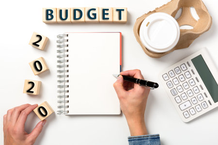 Budget planning for 2020. Office workplace table with calculator, pen, coffee and wooden blocks.