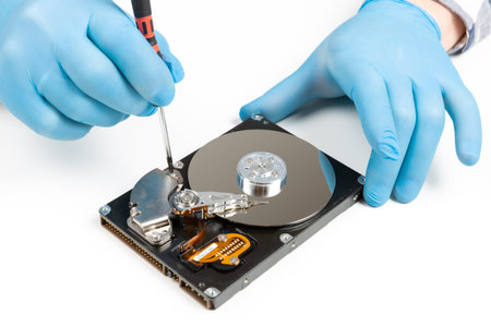 Men's hands in blue gloves repairing dismantled hard drive. Computer maintenance, technology concept