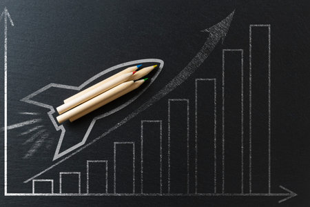 Drawing of a rocket on a black metal background with pencils. Startup concept