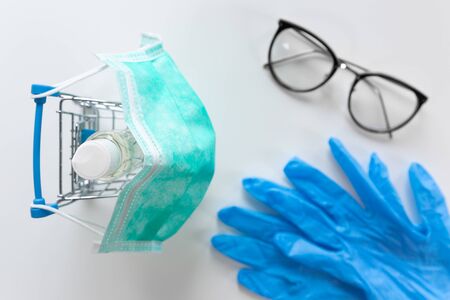 Shopping cart with facial mask hand sanitiser and blue gloves. Shopping and protection conceptの写真素材