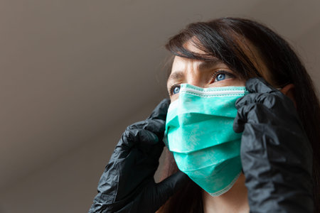 Women wearing a facial protction mask and black gloves.