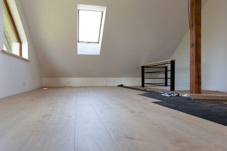 Construction worker installing laminate floor in a new renovated attic. Home improvement concept.の写真素材