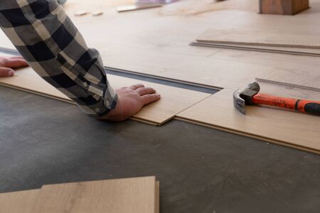 Construction worker installing laminate floor in a new renovated attic. Home improvement concept.の写真素材