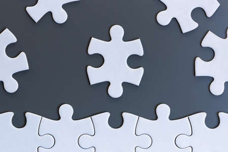 White jigsaw puzzle pieces on gray backgroundの写真素材