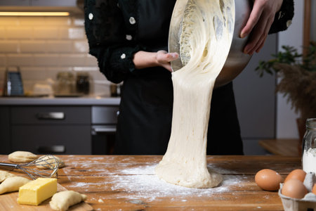 Young beautiful woman kneading dough at a wooden table in kitchen. Housewife hobbies concept.