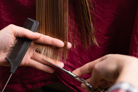 Closeup of hairdresser cutting blonde womens dry hair ends at home or salon.の写真素材