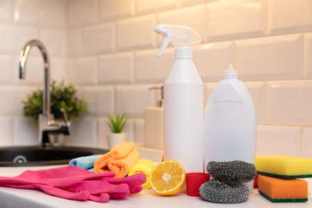 Cleaning products, citron and sponges on kitchen countertop with in background blurred sink.の写真素材