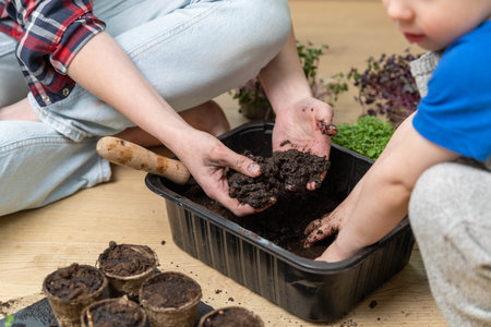 Sensory activities for child - young mother and son playing with dirt prepared for seeds. At home...
