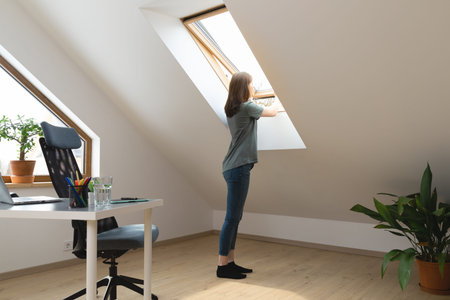 Women opening a window at home office and letting fresh air in. Healthy working environment in new...