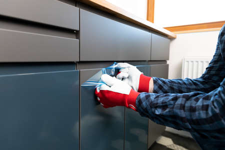 Home Improvement, handyman removing protective film on newly installed kitchen counter doors.の写真素材