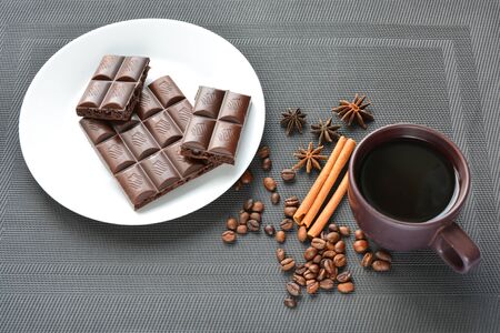 fragrant cup of coffee with porous chocolate among coffee beans, star anise and cinnamon sticks on a dark backgroundの写真素材