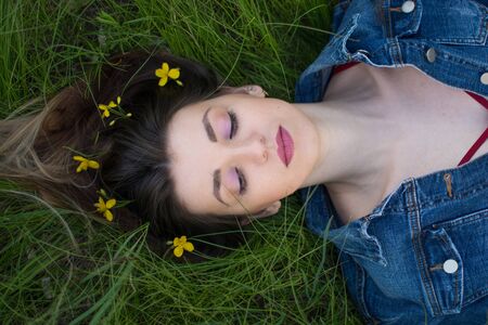 Girl with beautiful hair lying on her back in the green, juicy grass. Warm spring eveningの写真素材