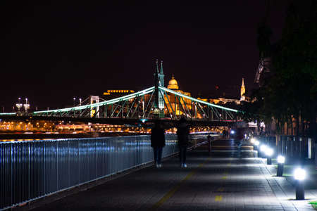 Budapest at night, two people walk along the Danube embankment.の写真素材