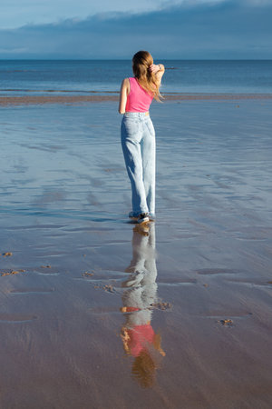 A girl walks along the coast of the North Sea in the UK.