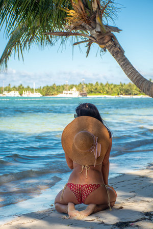 Dominican Republic of Punta Cana, a girl in a hat on the ocean with turquoise water and palm trees.の写真素材