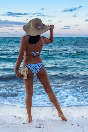Dominican Republic of Punta Cana, a girl in a hat on the ocean with turquoise water and palm trees.の写真素材