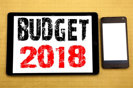 Hand writing text caption inspiration showing Budget 2018. Business concept for Household budgeting accounting planning Written on tablet, wooden background with sticky note and penの写真素材