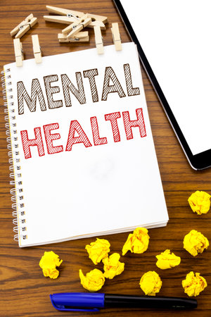 Writing text showing Mental Health. Business concept for Anxiety Illness Disorder written on note paper folded Meaning Thinking paper on the wooden background with marker and coffeeの写真素材