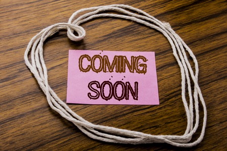 Handwritten text showing Coming Soon. Business concept for Message Future written on sticky note paper on dark wooden background. With heart meaning love or adoration.の写真素材