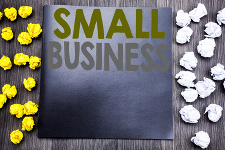 Hand writing text caption inspiration showing Small Business. Business concept for Family Owned Company Written on notepad note notebook wooden background with sticky folded yellow and whiteの写真素材