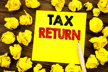 Writing text showing Tax Return. Business concept for Taxation Refund Written on sticky note paper, wooden background folded yellow paper meaning thinkingの写真素材
