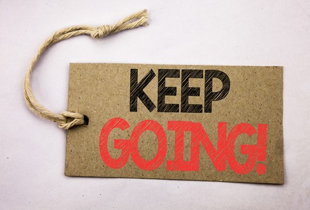 Hand writing text caption inspiration showing Keep Going. Business concept for Go Moving Forward Letting written on price tag paper on white vintage background.の写真素材