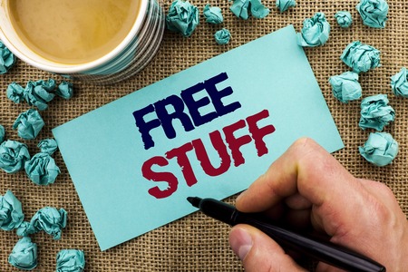 Writing note showing  Free Stuff. Business photo showcasing Complementary Free of Cost Chargeless Gratis Costless Unpaid written by Man Holding Pen Sticky Note Paper the jute background Cupの写真素材