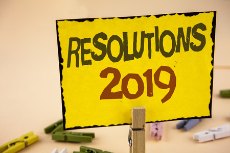 Handwriting text writing Resolutions 2019. Concept meaning Positive reinforcement personal improvent corporate goals written Yellow Sticky Note Paper the plain background Wooden Clips.の写真素材