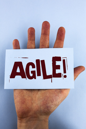 Word writing text Agile Motivational Call. Business concept for Develop an agility towards technological chnage written Sticky Note Paper placed Hand the plain background.の写真素材