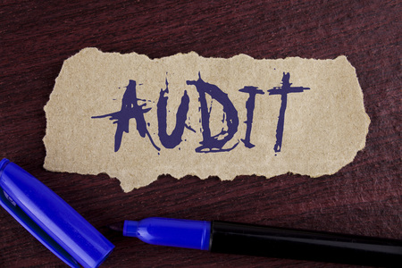 Handwriting text writing Audit. Concept meaning Local company auditors perform their financial investigation annually written Tear Cardboard paper piece wooden background Marker next to it.の写真素材