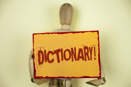 Conceptual hand writing showing Dictionary Motivational Call. Business photo text Learning another vocabs and synonyms from book written Sticky Note paper plain background Wooden Robot Toy.の写真素材