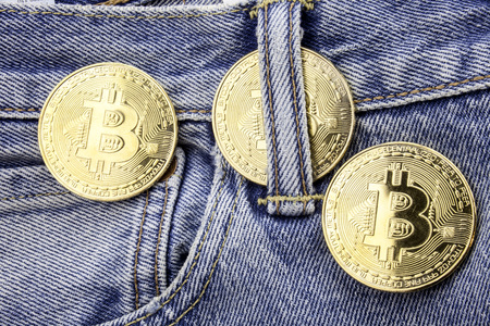 Three golden bitcoins on the jeans pants. Making online money concept. How to make money conceptual image. Mining golden bitcoins on the internet. Easy money on the internet concept.の写真素材