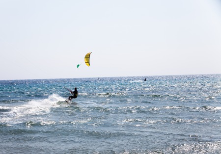 Active man Kitesurfing on the beach with kite. Extreme water sports. Summer vacation leisure time. Kiteboarding. Professional Kite-surfer in action on waveの写真素材