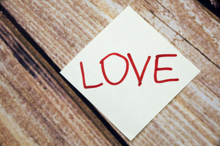 Handwritten paper with love concept on the wooden background. Retro background with word Love. Valentines day concept with wooden backgroundの写真素材