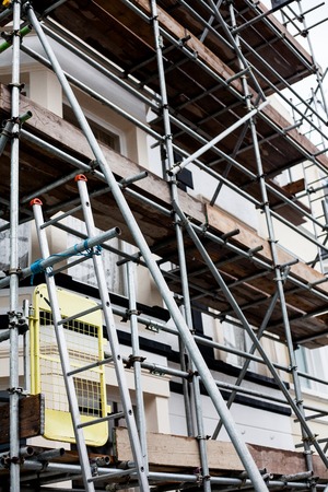 Restoring and repairing building facade. Building under repair and construction. Construction and repair building on the street with metal protection.の写真素材