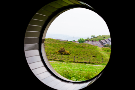 Green grass on the meadow field with sea in the background. Composition through the round window. Scenery with meadow and beautiful nature. Beautiful landscape composition with blue sky.の写真素材