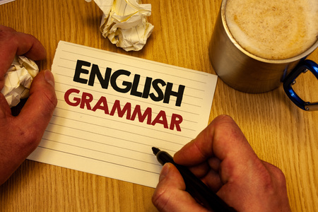 Handwriting text writing English Grammar. Concept meaning Language Knowledge School Education Literature Reading Man holding pen ideas notebook crumpled papers coffee cup wooden backgroundの写真素材