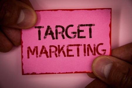 Handwriting text Target Marketing. Concept meaning Market Segmentation Audience Targeting Customer Selection Words written pink paper note red border fingers holding corners messageの写真素材