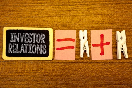 Handwriting text Investor Relations. Concept meaning Finance Investment Relationship Negotiate Shareholder White paper clip laid woody desk black slate some texts equal and plus markの写真素材