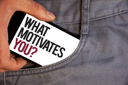 Word writing text What Motivates You Question. Business concept for Passion Drive Incentive Dream Aspiration Personage hand pushing mobile phone into back pocket fascinating wayの写真素材