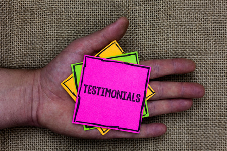 Text sign showing Testimonials. Conceptual photo Customers formal endorsement statement experience of someone Holding small pitches art papers thoughts ideas memories mat black shadowの写真素材