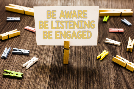 Text sign showing Be Aware Be Listening Be Engaged. Conceptual photo take attention to actions or speakers Clothespin holding white paper note several clothespins wooden floorの写真素材